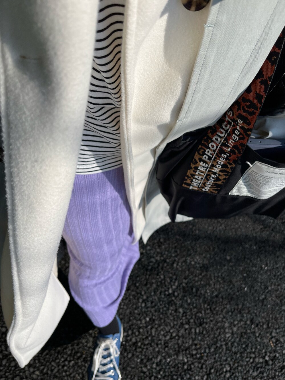 グリーン系のステンカラーコート、ホワイト系のベスト、ホワイト系のTシャツ/カットソーを着用したレディースの春コーディネートの2枚目の写真