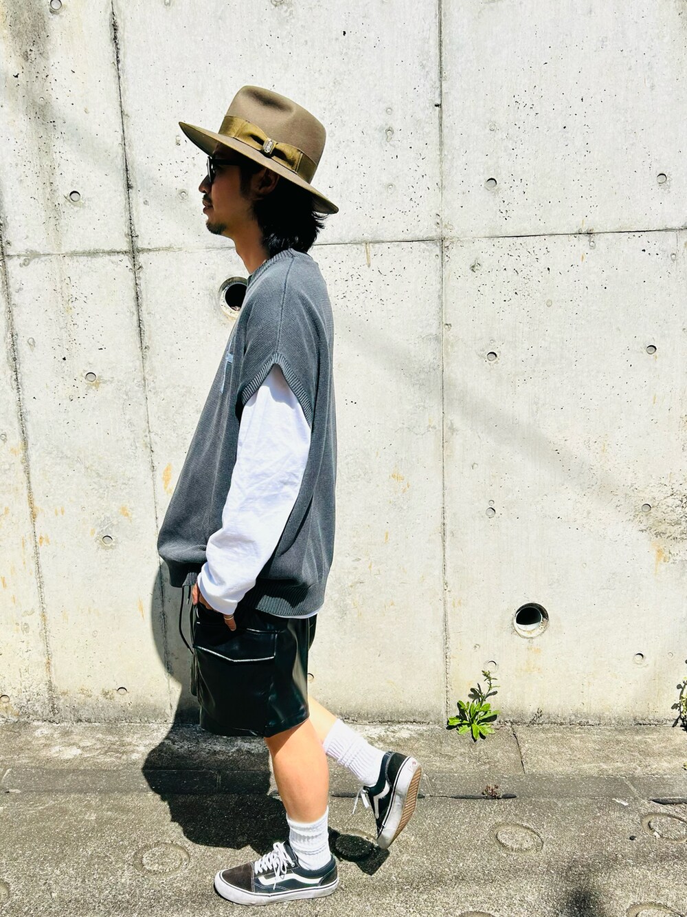 グレー系のトップス、ブラック系のスニーカー、グリーン系のハットを着用したメンズの春コーディネートの3枚目の写真