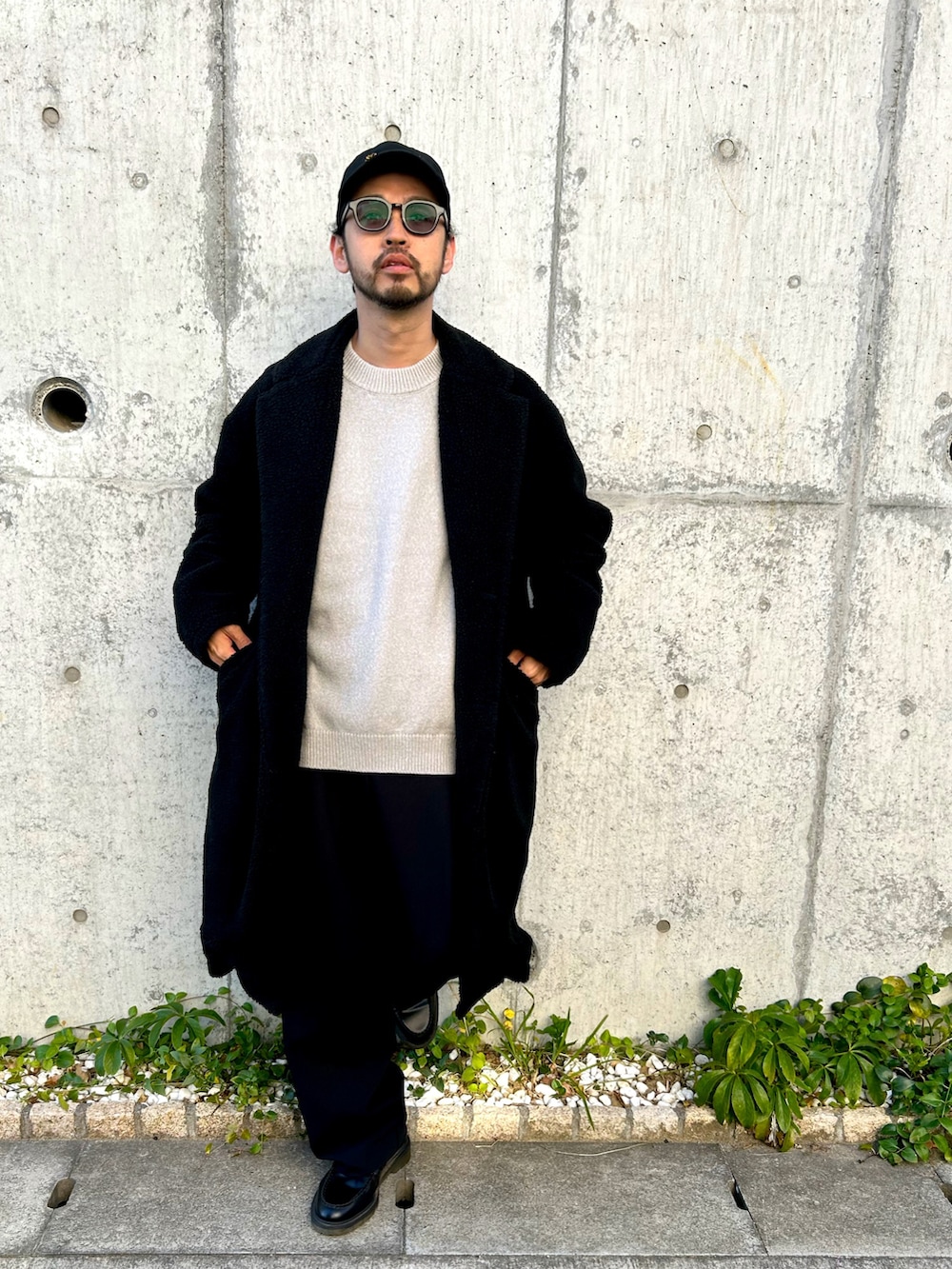 グレー系のニット/セーター、ブラック系のチェスターコート、ブラック系のスラックスを着用したメンズの冬コーディネートの2枚目の写真