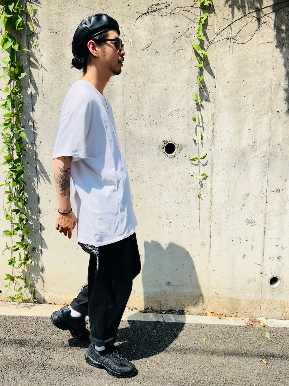 ブラック系のスニーカー、ホワイト系のTシャツ/カットソー、ブラック系のパンツを着用したメンズの夏コーディネートの2枚目の写真