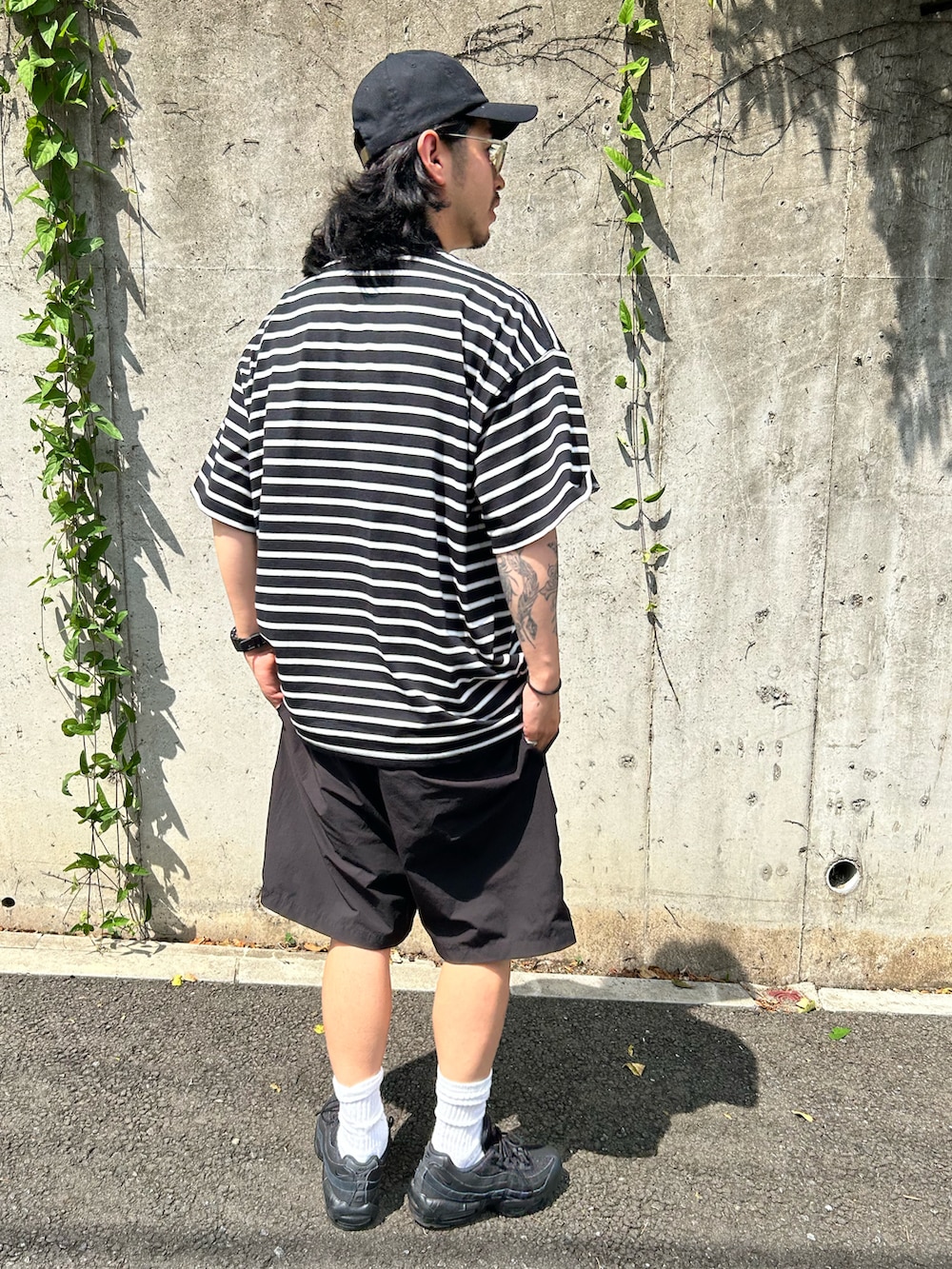 ブラック系のTシャツ/カットソー、ブラック系のパンツ、ブラック系のスニーカーを着用したメンズの夏コーディネートの3枚目の写真