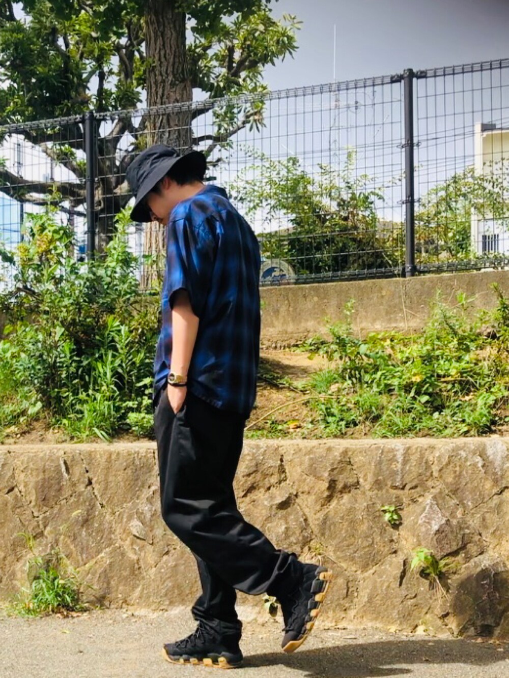 ブルー系のトップス、ブラック系のスニーカー、ブラック系のチノパンツを着用したメンズの夏コーディネートの2枚目の写真