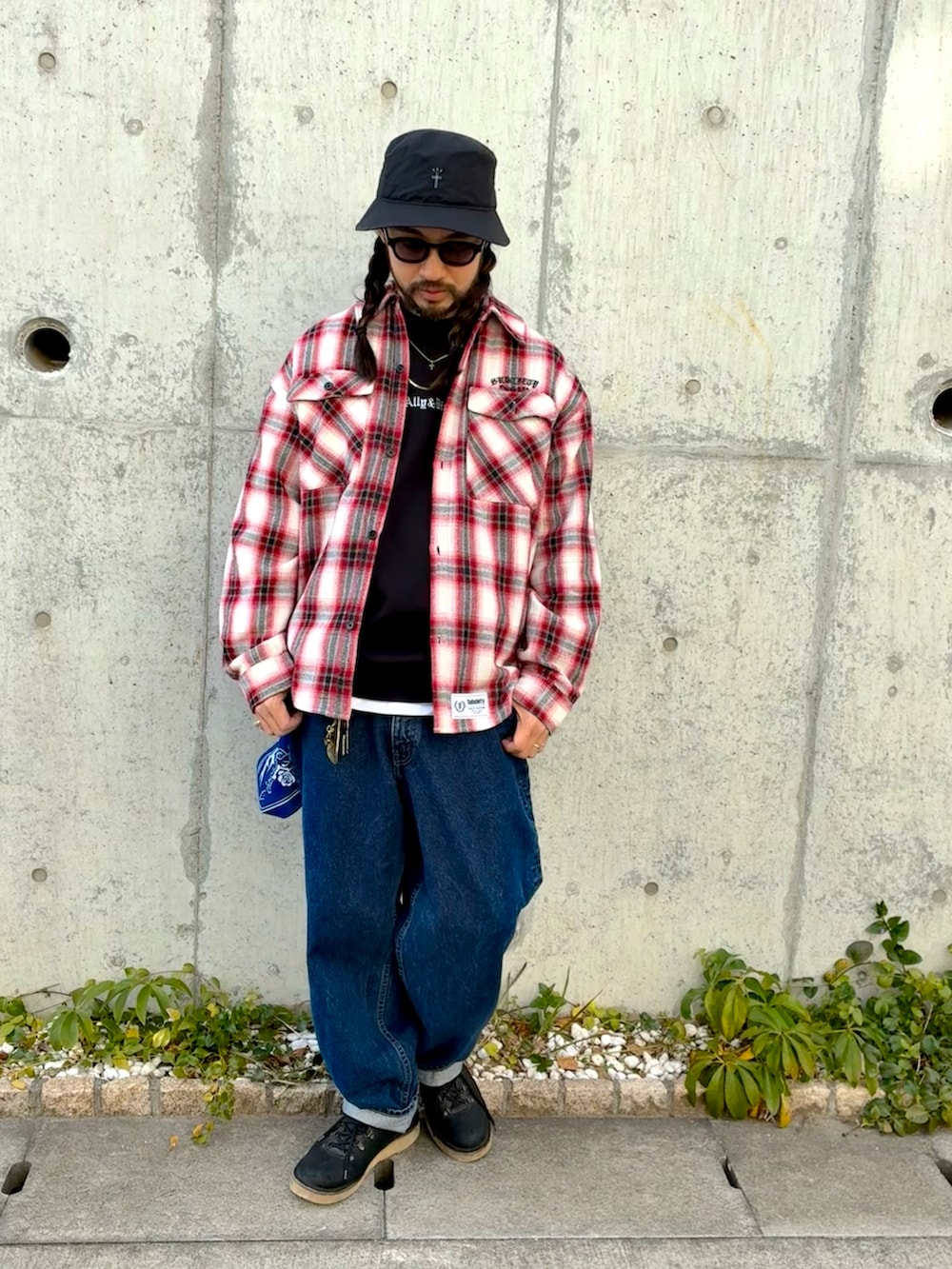 レッド系のブルゾン、ブルー系のデニムパンツ、ブラック系のブーツを着用したメンズの冬コーディネートの2枚目の写真