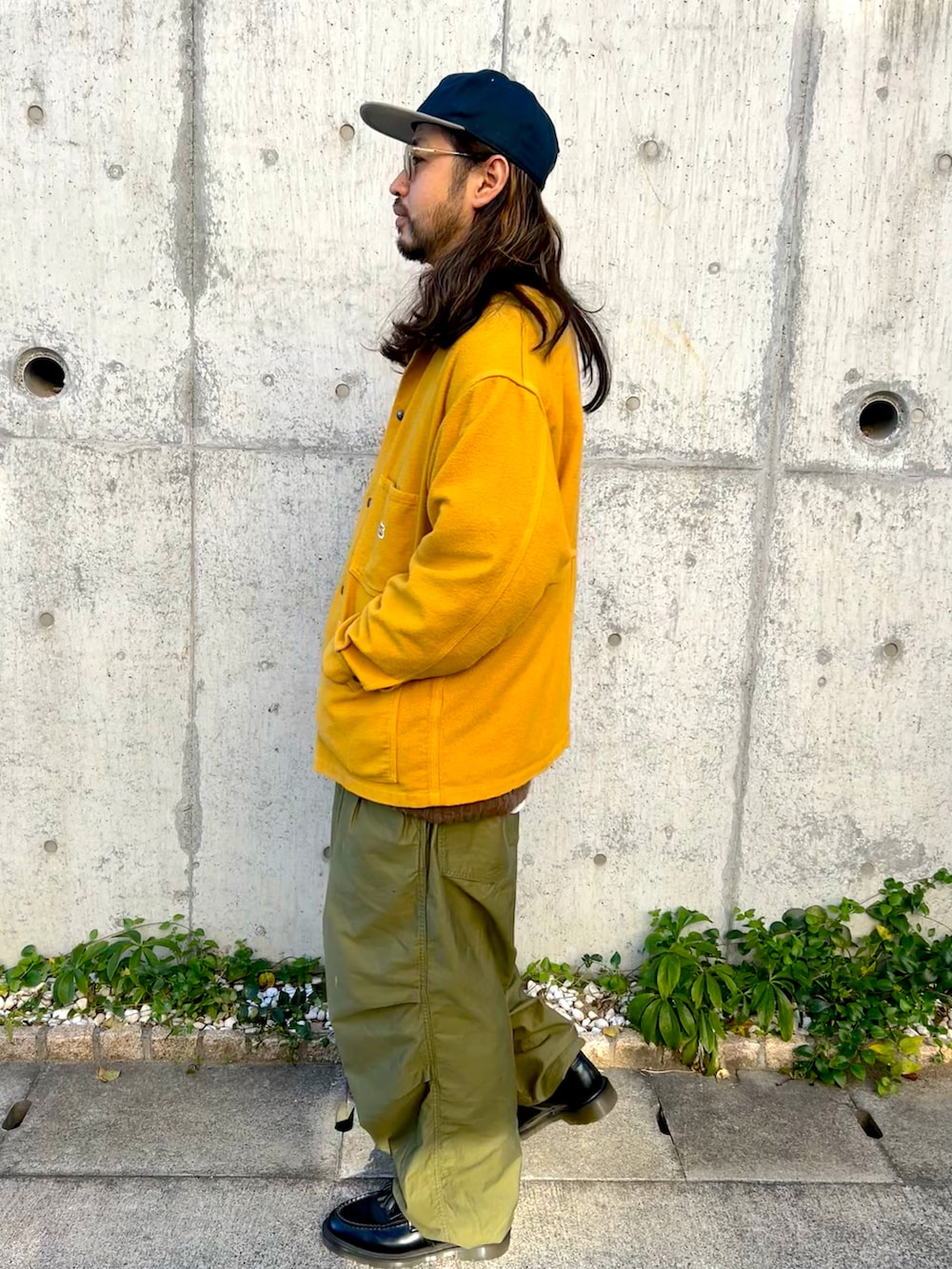 イエロー系のカバーオール、グリーン系のカーゴパンツ、ブラック系のローファーを着用したメンズの冬コーディネートの2枚目の写真