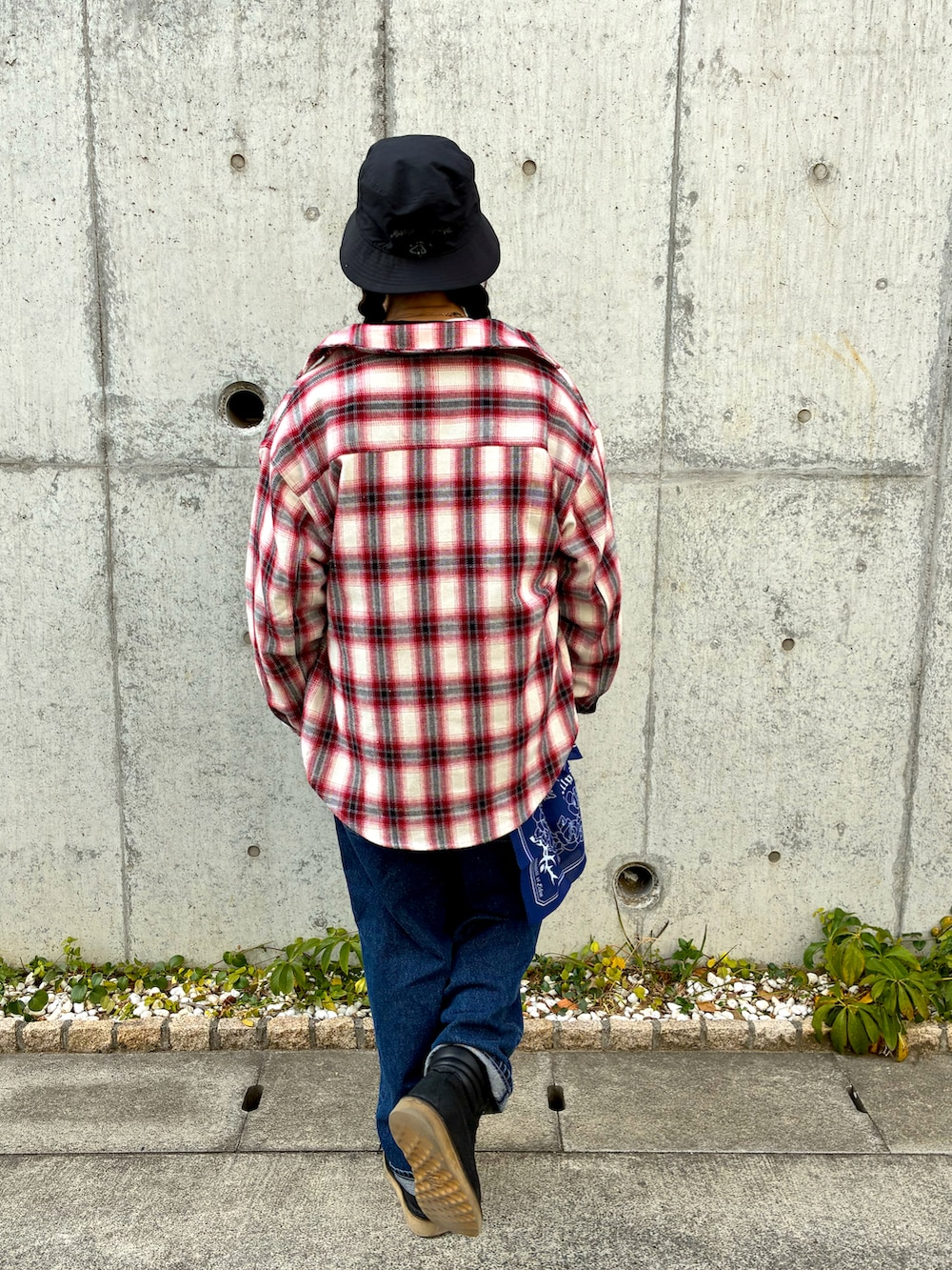 レッド系のブルゾン、ブルー系のデニムパンツ、ブラック系のブーツを着用したメンズの冬コーディネートの4枚目の写真