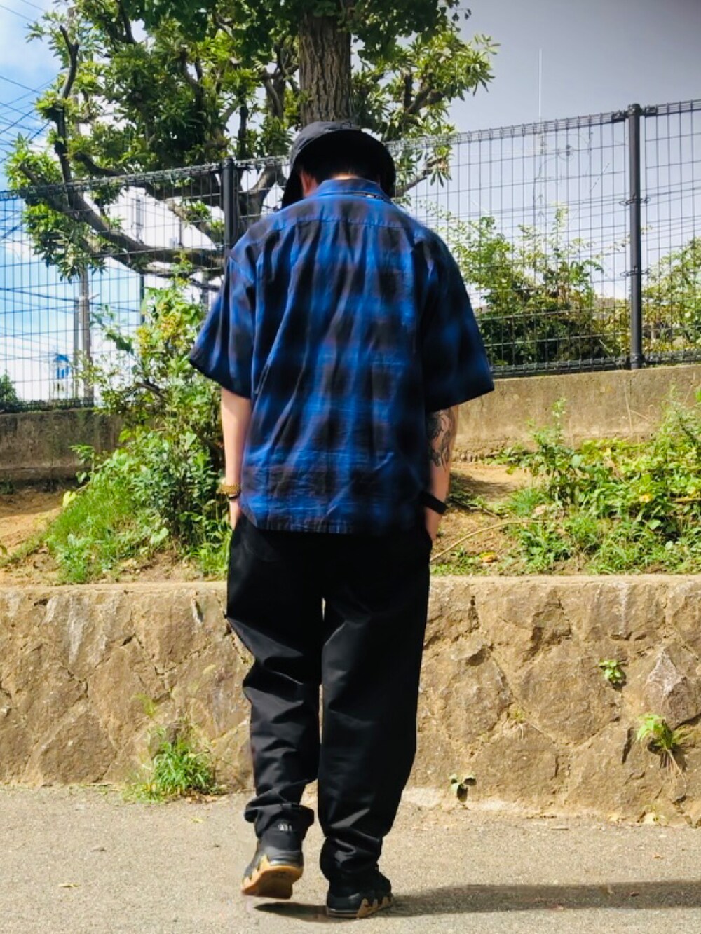 ブルー系のトップス、ブラック系のスニーカー、ブラック系のチノパンツを着用したメンズの夏コーディネートの4枚目の写真