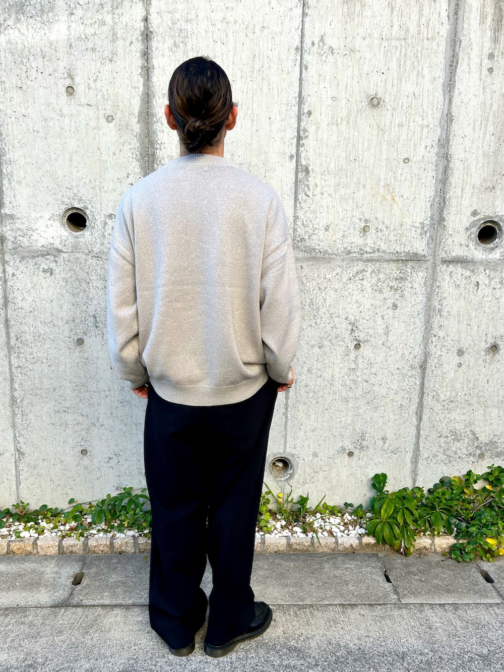 グレー系のニット/セーター、ブラック系のチェスターコート、ブラック系のスラックスを着用したメンズの冬コーディネートの4枚目の写真