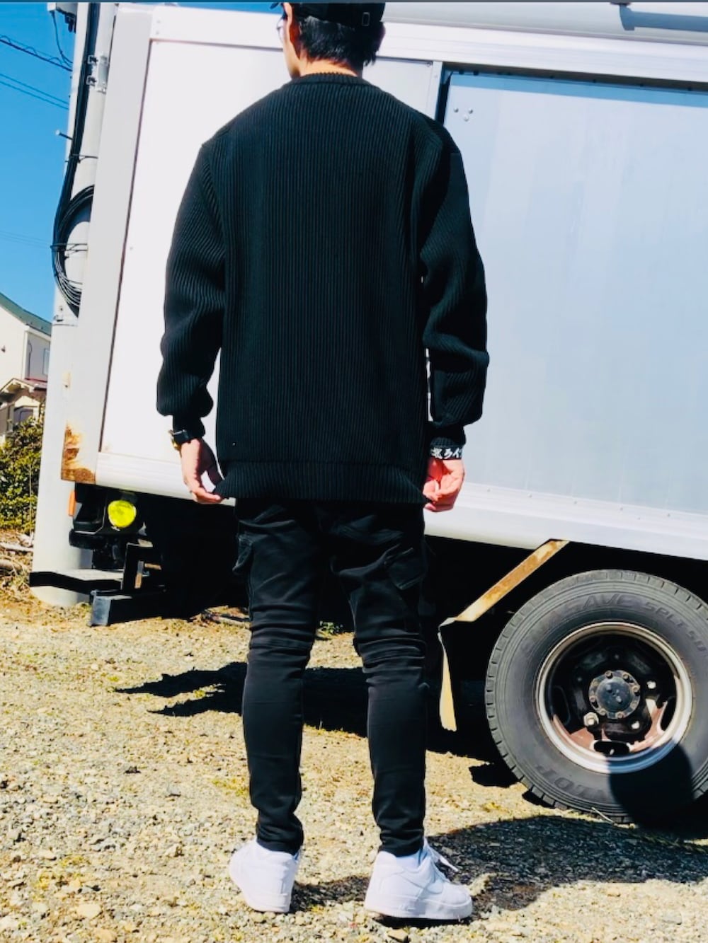 ブラック系のニット/セーター、ブラック系のカーゴパンツ、ホワイト系のスニーカーを着用したメンズの春コーディネートの3枚目の写真