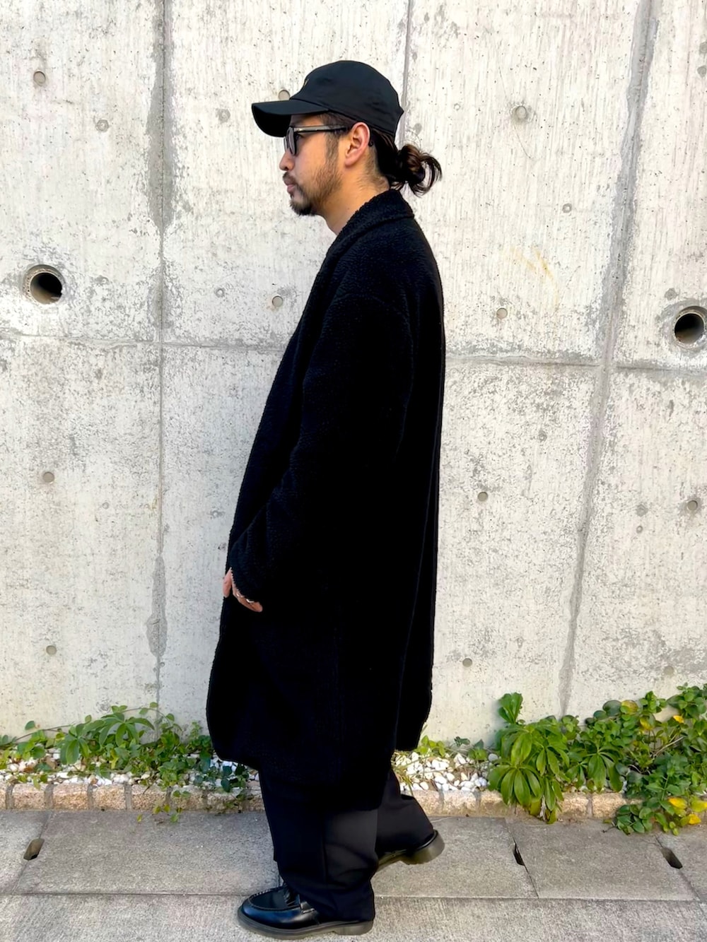 グレー系のニット/セーター、ブラック系のチェスターコート、ブラック系のスラックスを着用したメンズの冬コーディネートの3枚目の写真