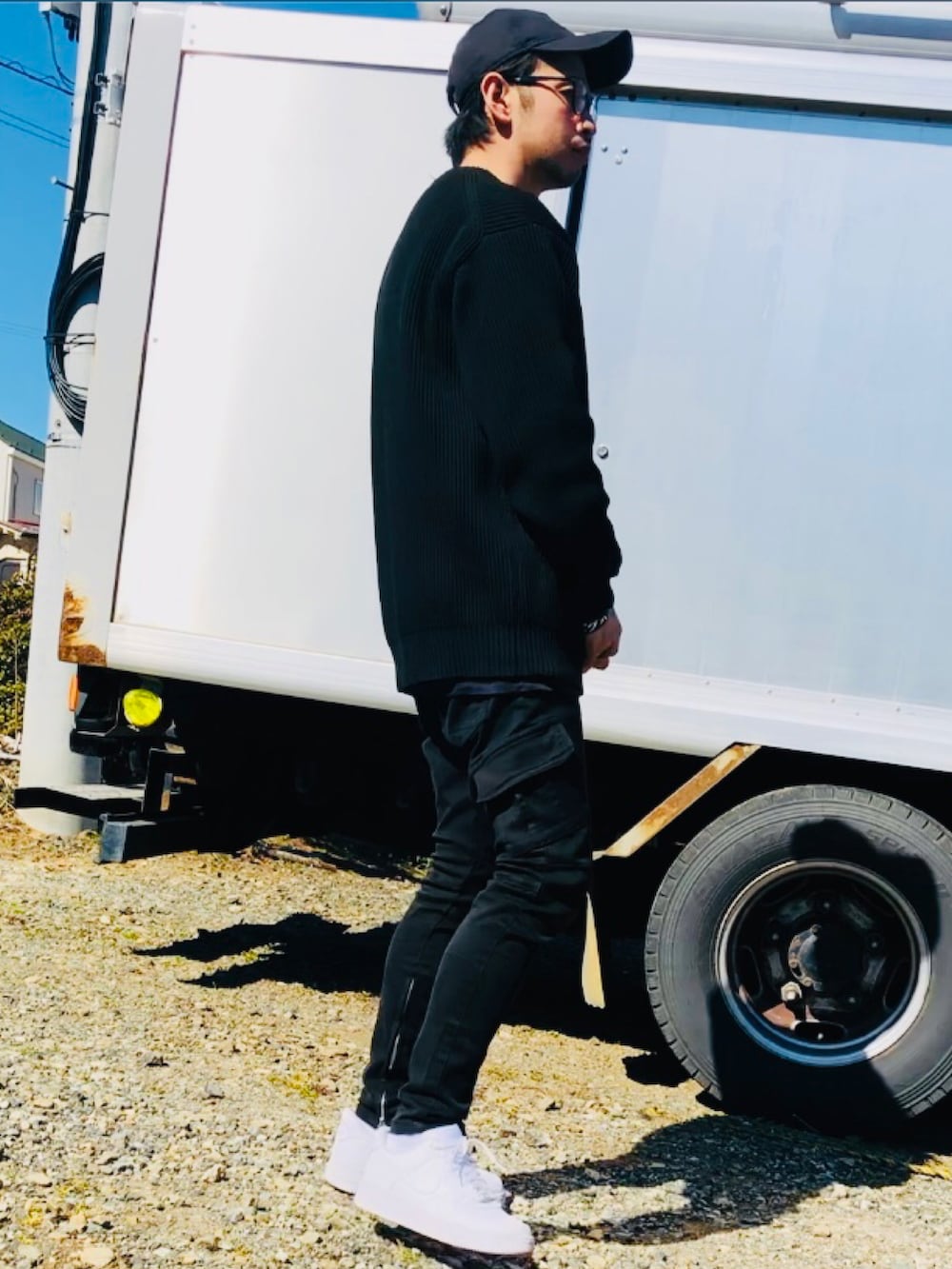 ブラック系のニット/セーター、ブラック系のカーゴパンツ、ホワイト系のスニーカーを着用したメンズの春コーディネートの2枚目の写真