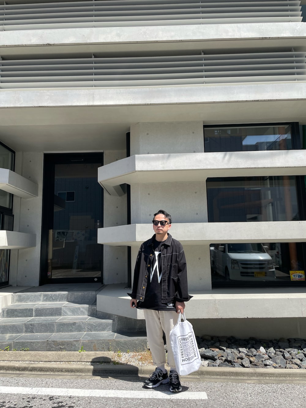 ホワイト系のその他パンツ、ブラック系のスニーカー、その他のトートバッグを着用したメンズの春コーディネートの3枚目の写真