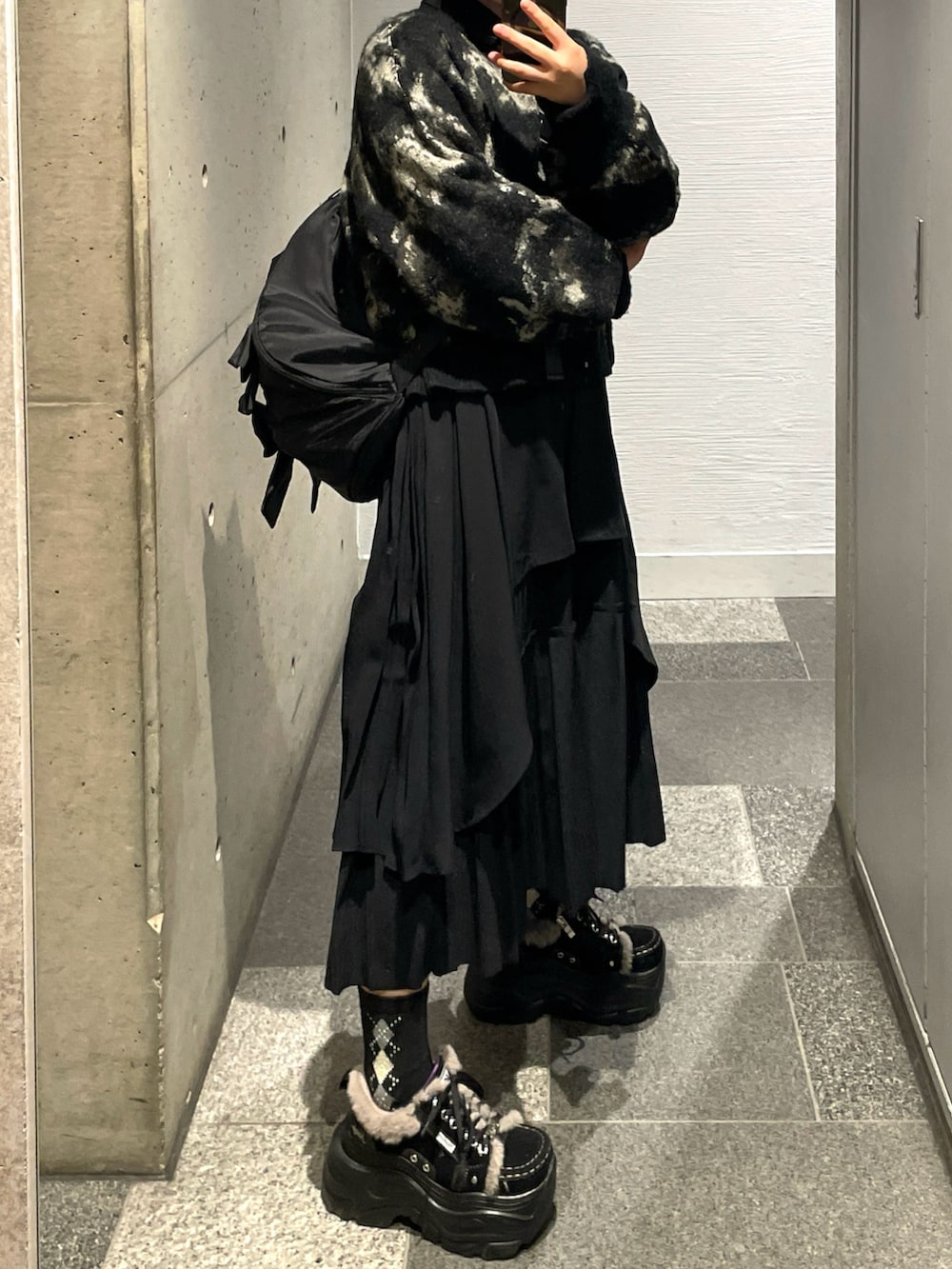 ブラック系のスニーカー、ブラック系のニット/セーター、ブラック系のショルダーバッグを着用したレディースの秋コーディネートの3枚目の写真