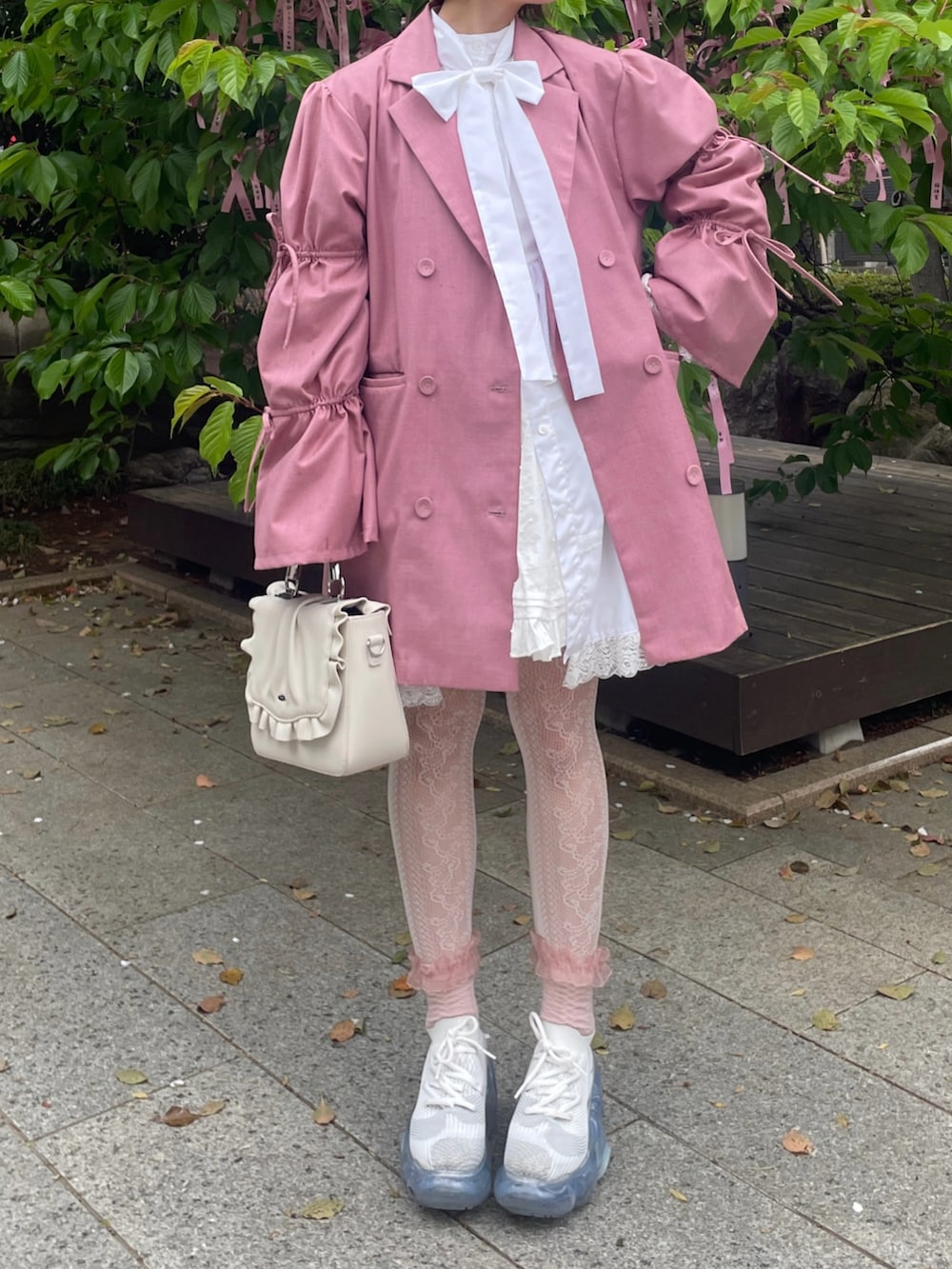 ホワイト系のスニーカー、ホワイト系のハンドバッグ、ピンク系のテーラードジャケットを着用したレディースの春コーディネートの2枚目の写真