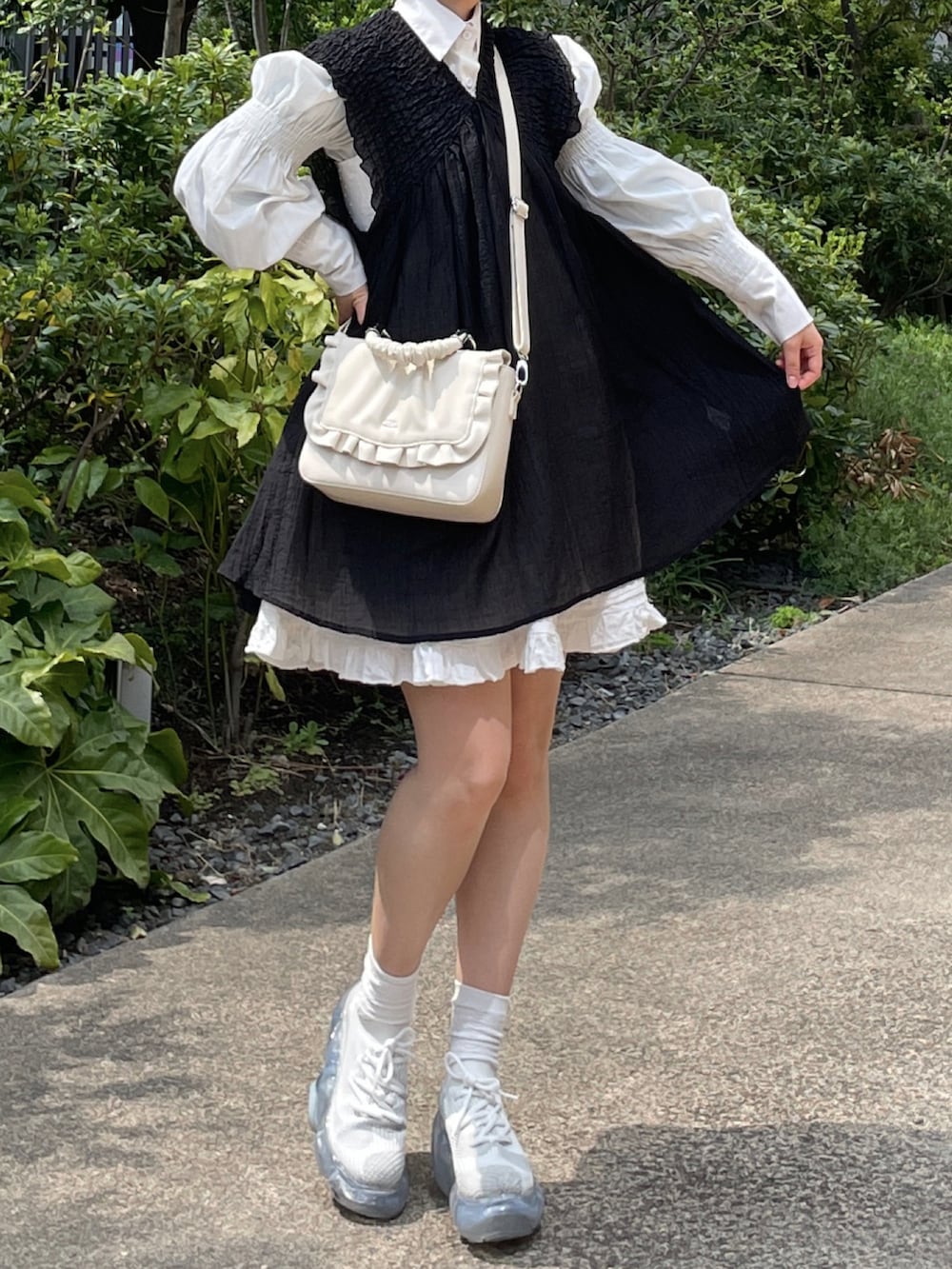 ホワイト系のスニーカー、ホワイト系のワンピース、ブラック系のワンピースを着用したレディースの春コーディネートの3枚目の写真