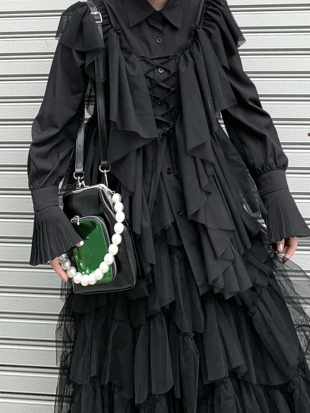 ブラック系のベスト、ブラック系のスカート、ブラック系のスニーカーを着用したレディースの春コーディネートの2枚目の写真