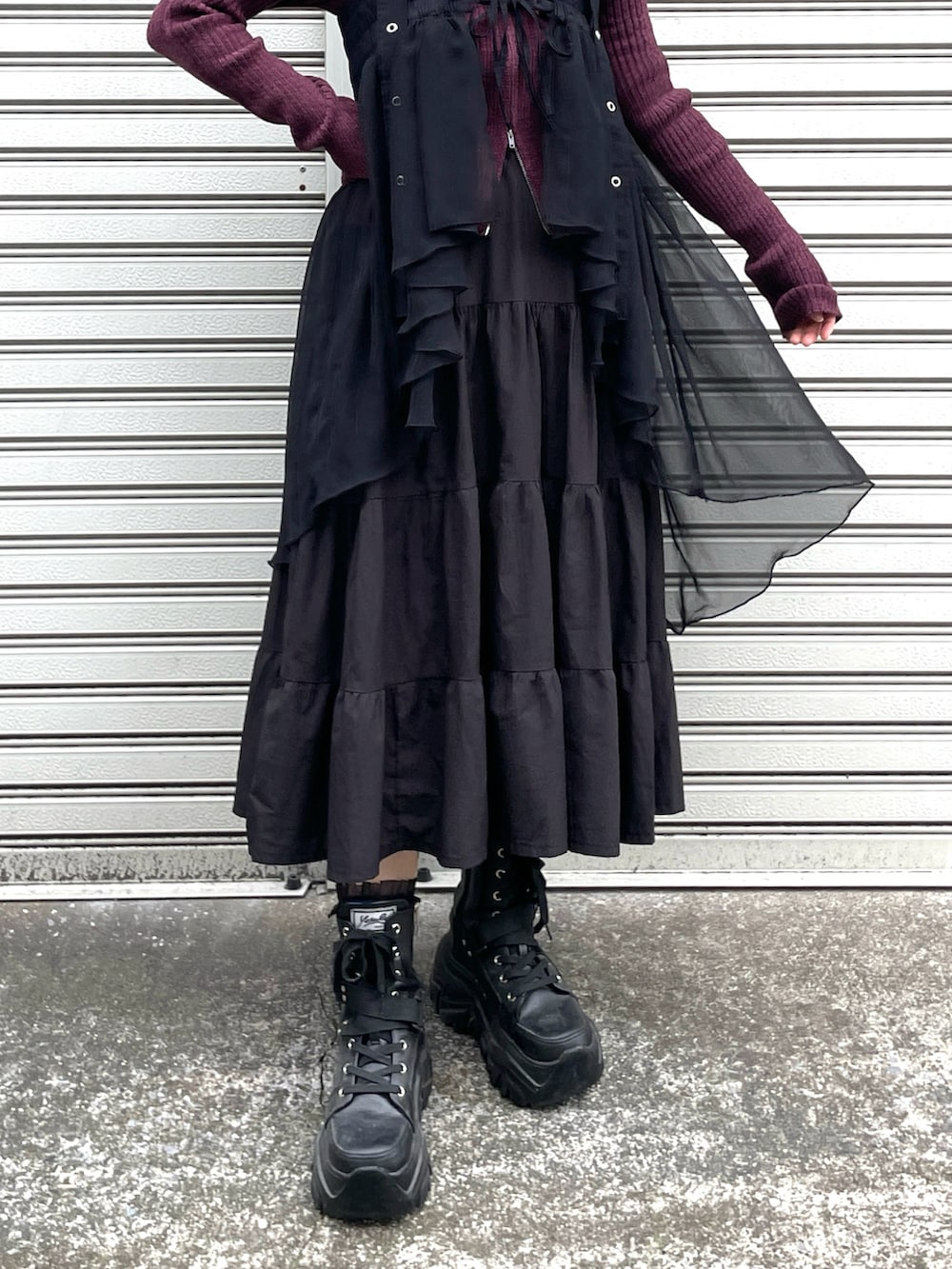 レッド系のカーディガン/ボレロ、ブラック系のスカート、ブラック系のブーツを着用したレディースの秋コーディネートの2枚目の写真