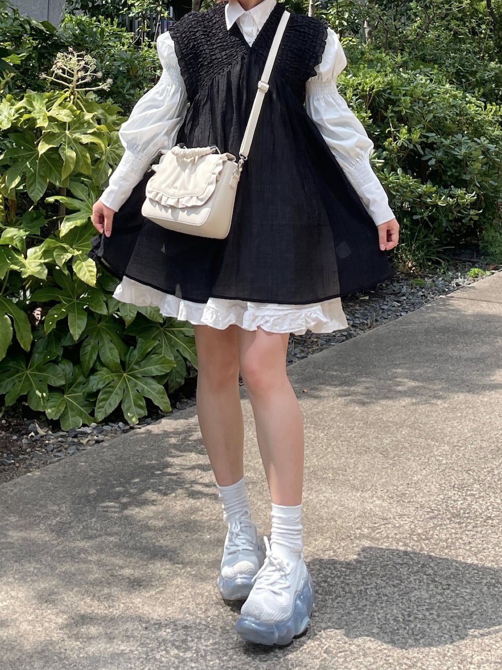 ホワイト系のスニーカー、ホワイト系のワンピース、ブラック系のワンピースを着用したレディースの春コーディネートの2枚目の写真