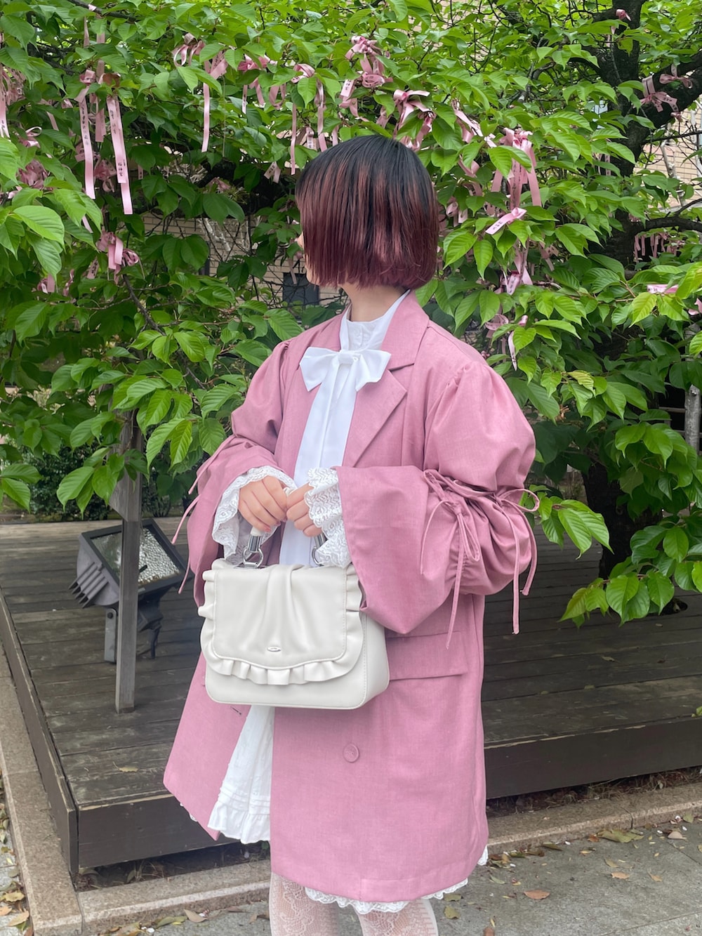 ホワイト系のスニーカー、ホワイト系のハンドバッグ、ピンク系のテーラードジャケットを着用したレディースの春コーディネートの3枚目の写真