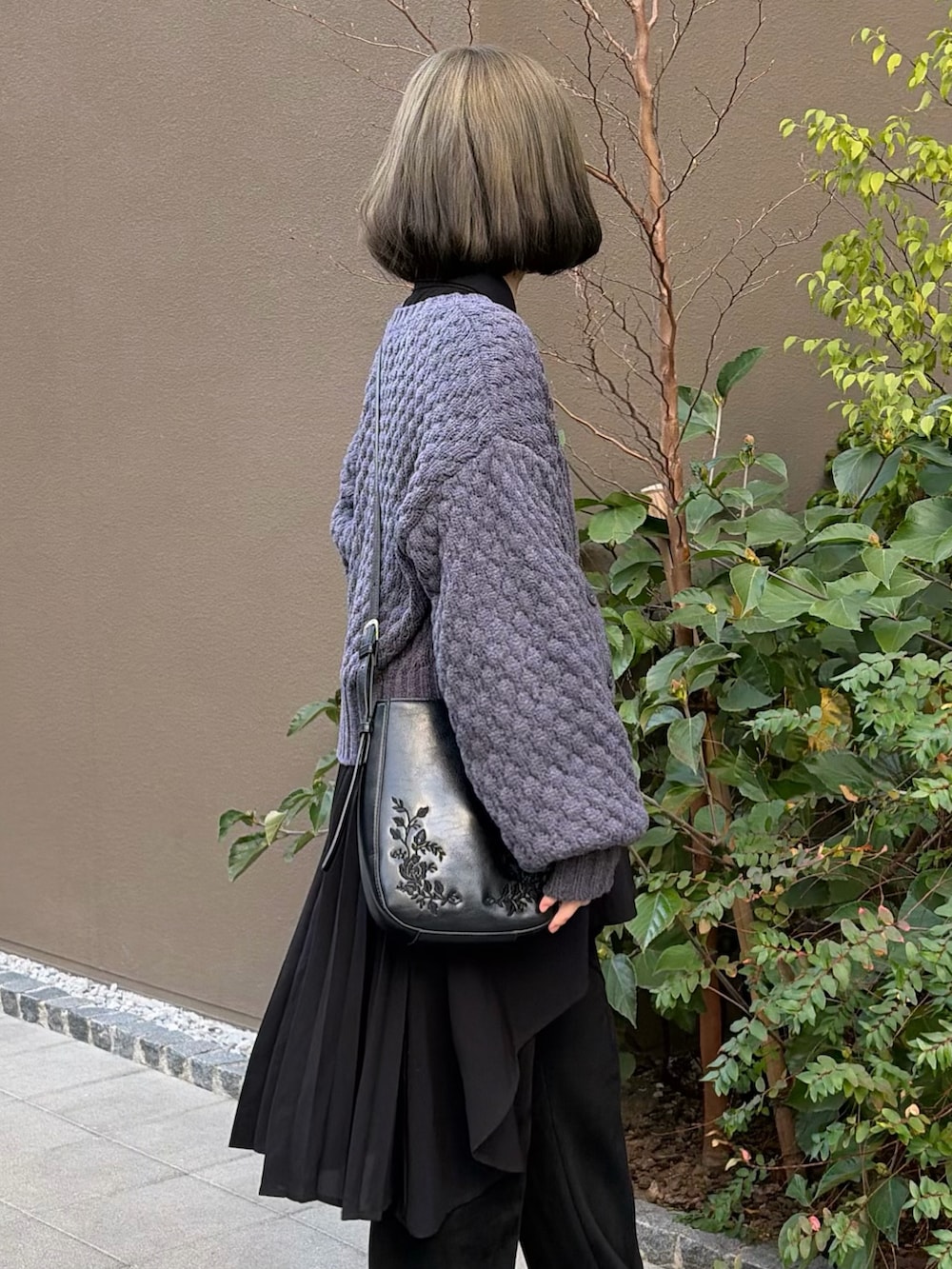 グレー系のニット/セーター、ブラック系のスラックス、ブラック系のショルダーバッグを着用したレディースの冬コーディネートの3枚目の写真
