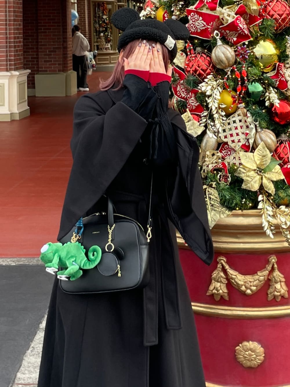 ブラック系のステンカラーコート、ブラック系のショルダーバッグ、ブラック系のスニーカーを着用したレディースの冬コーディネートの3枚目の写真