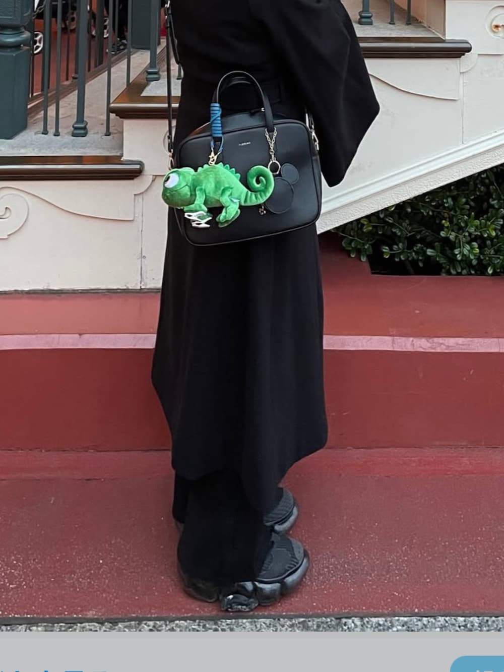 ブラック系のステンカラーコート、ブラック系のショルダーバッグ、ブラック系のスニーカーを着用したレディースの冬コーディネートの2枚目の写真