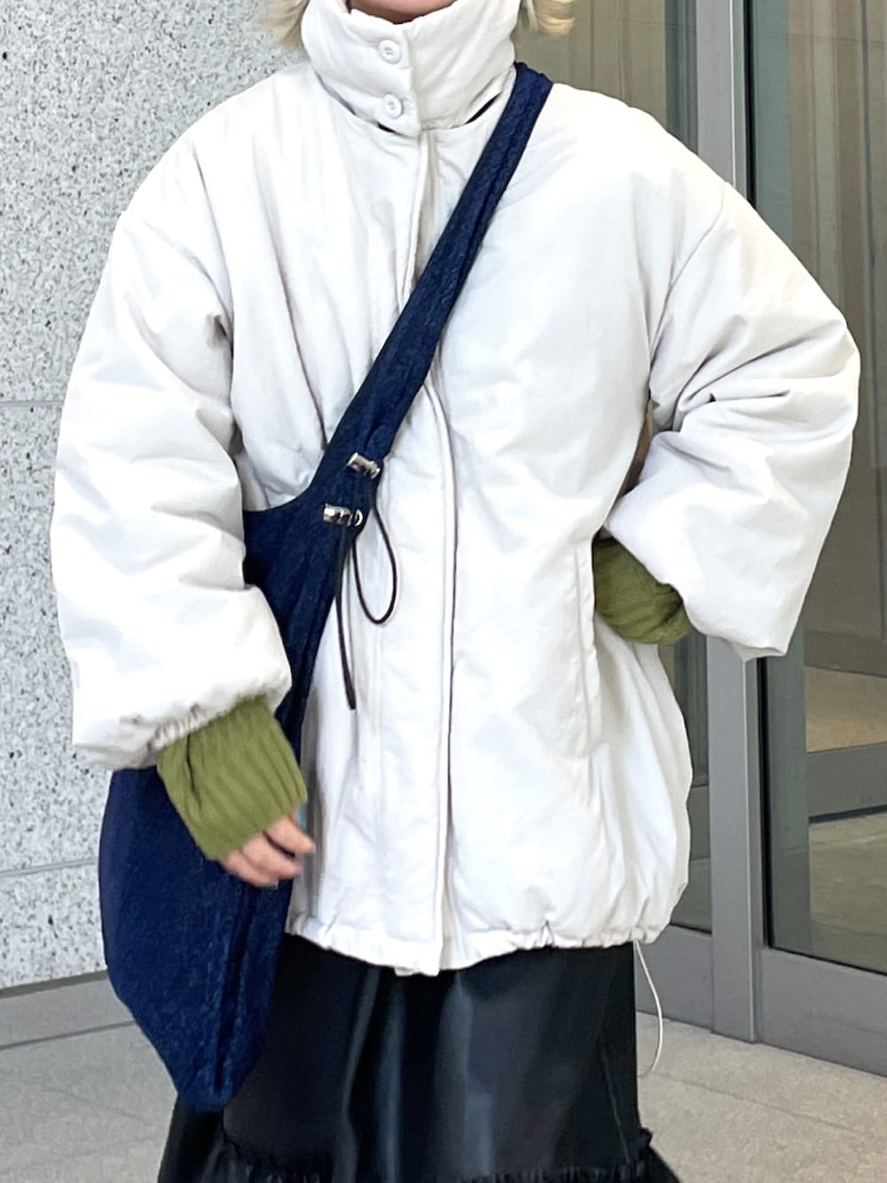 ホワイト系のブルゾン、ブルー系のトートバッグ、グリーン系のニット/セーターを着用したレディースの冬コーディネートの3枚目の写真