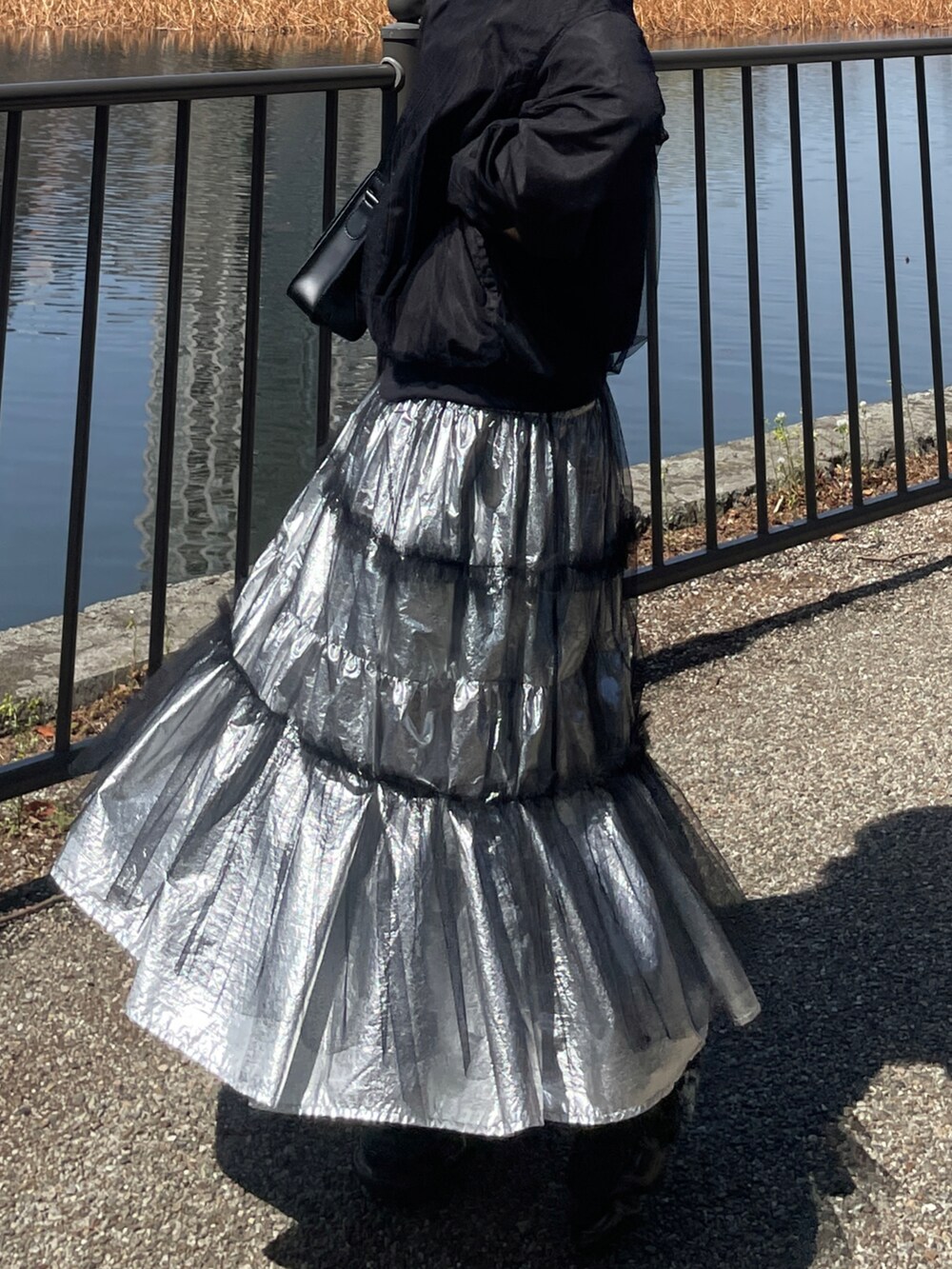 ブラック系のブルゾン、シルバー系のスカート、ブラック系のボディバッグ/ウエストポーチを着用したレディースの春コーディネートの3枚目の写真