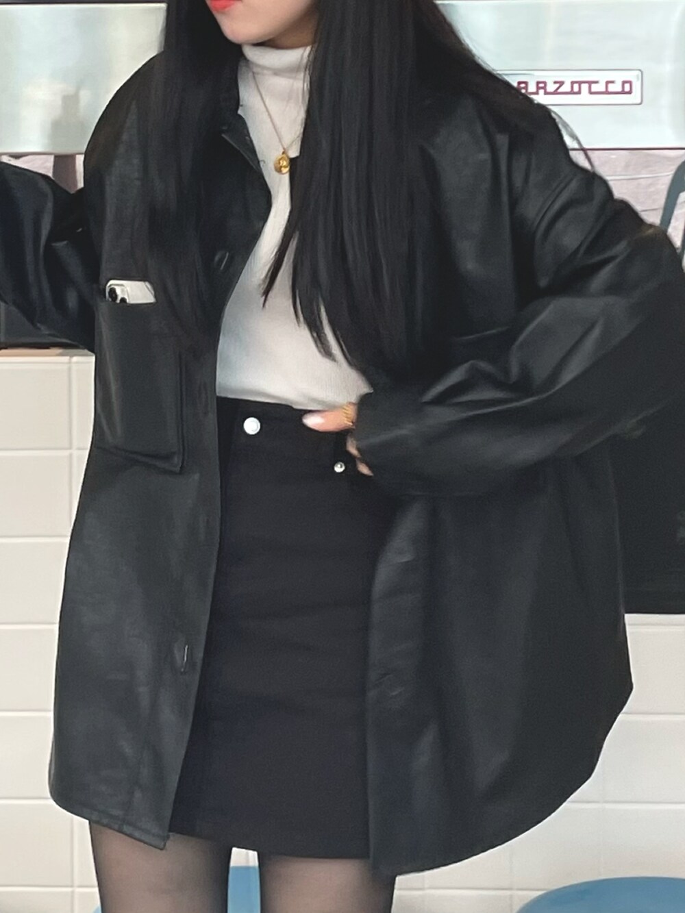 ブラック系のカバーオール、ブラック系のデニムスカート、ブラック系のブーツを着用したレディースの秋コーディネートの2枚目の写真