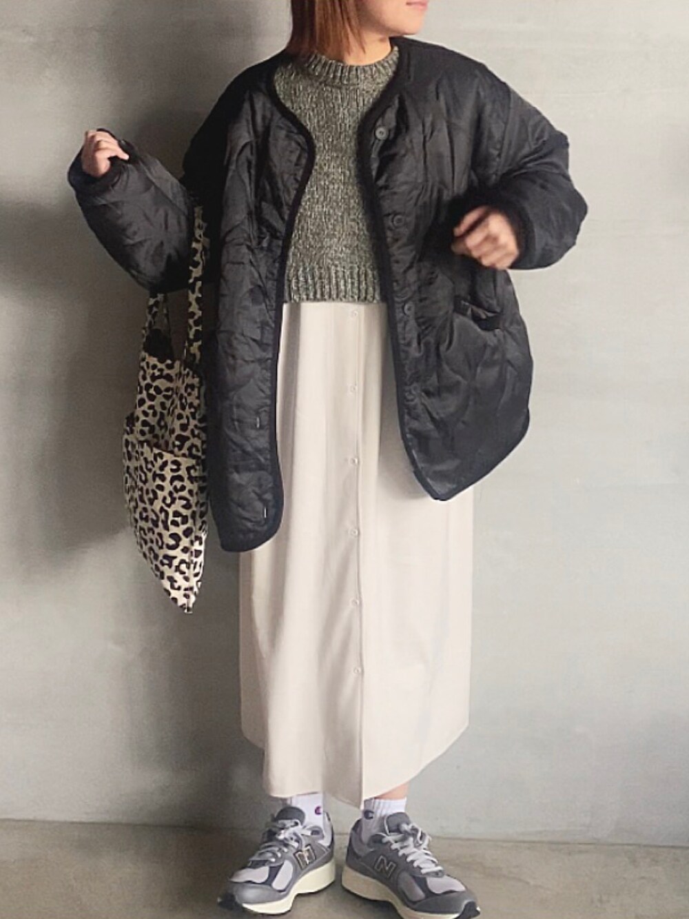 グレー系のノーカラージャケット、ブラック系のスカート、グレー系のスニーカーを着用したレディースの冬コーディネートの2枚目の写真