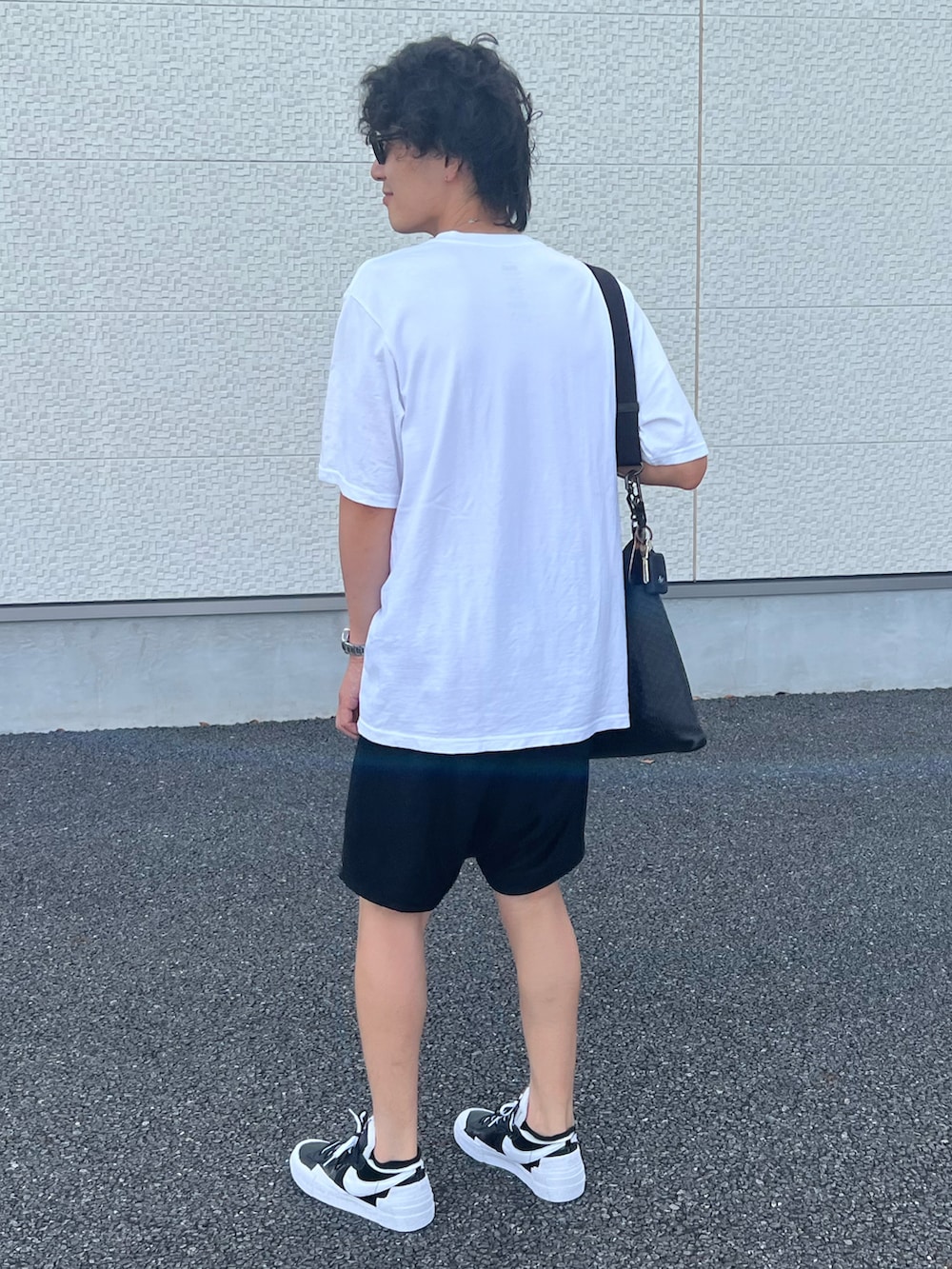 ホワイト系のTシャツ/カットソー、ブラック系のショルダーバッグ、ブラック系のパンツを着用したメンズの夏コーディネートの2枚目の写真