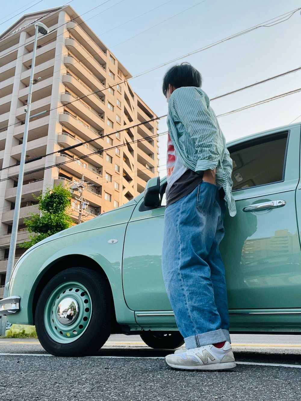 ブルー系のデニムパンツ、ホワイト系のスニーカー、その他のトップスを着用したメンズの夏コーディネートの2枚目の写真