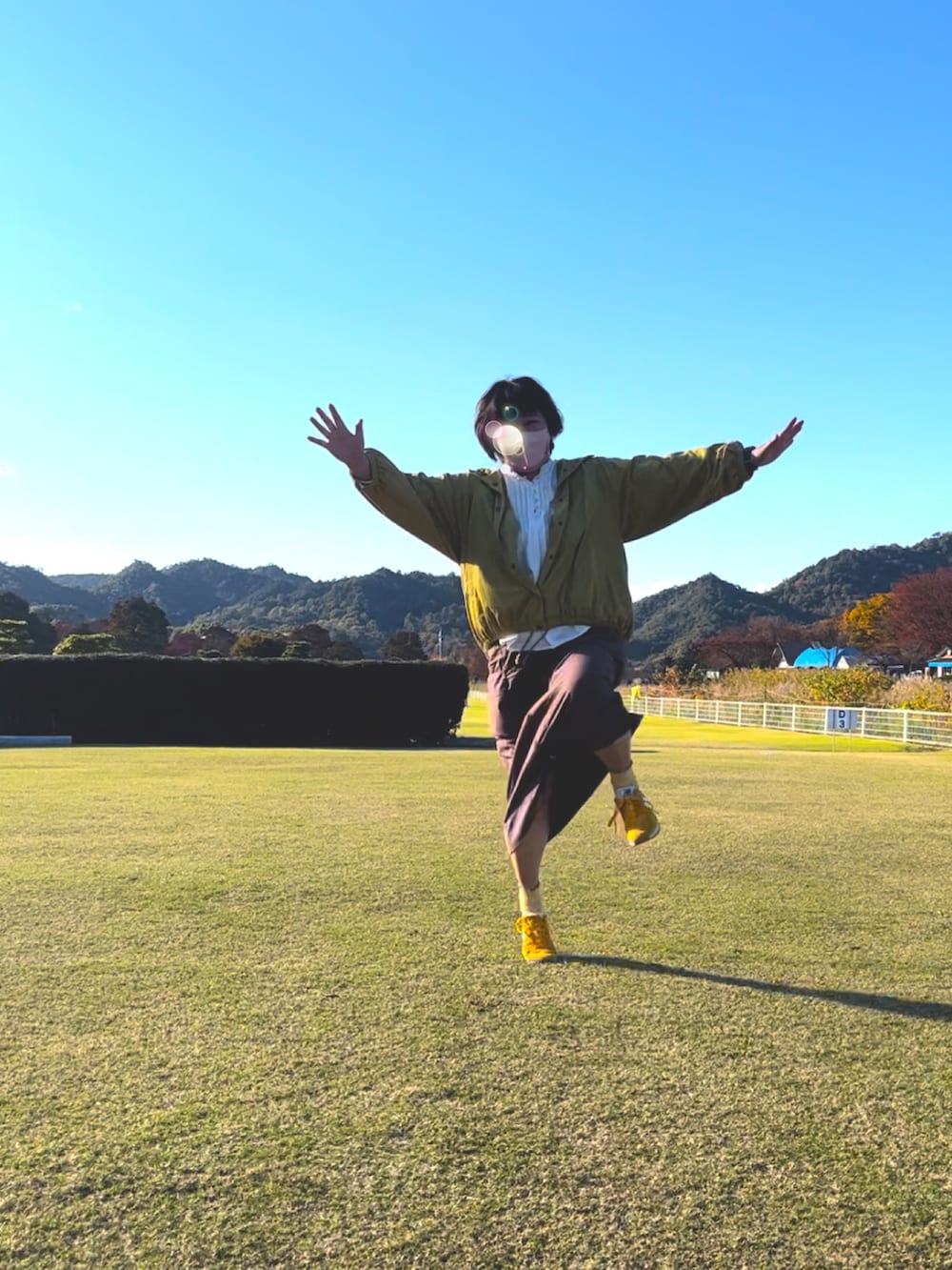 イエロー系のブルゾン、ブラウン系のスカート、ホワイト系のシャツ/ブラウスを着用したレディースの秋コーディネートの2枚目の写真