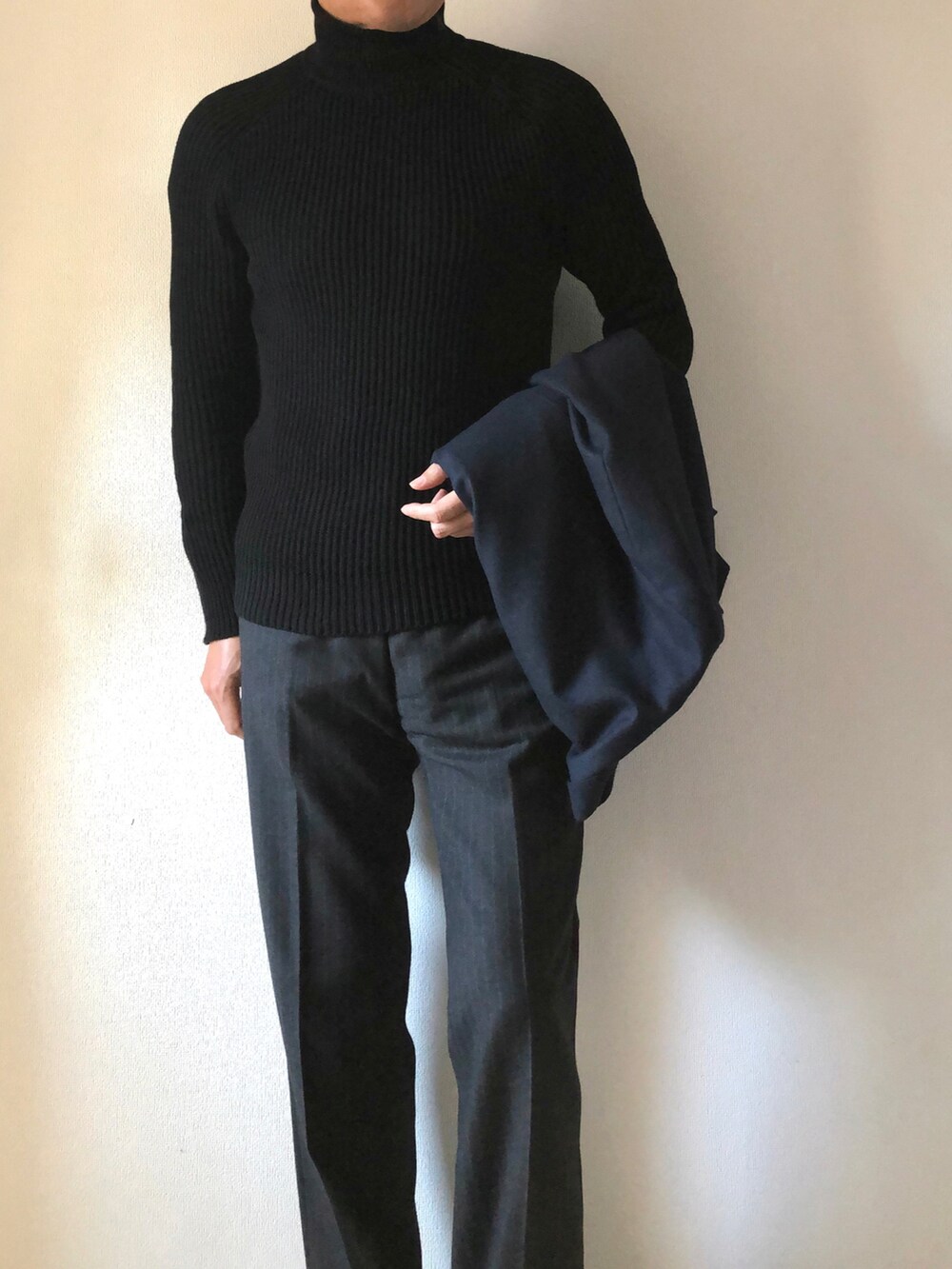 ブラック系のニット/セーター、グレー系のスラックス、ブルー系のテーラードジャケットを着用したメンズの冬コーディネートの2枚目の写真