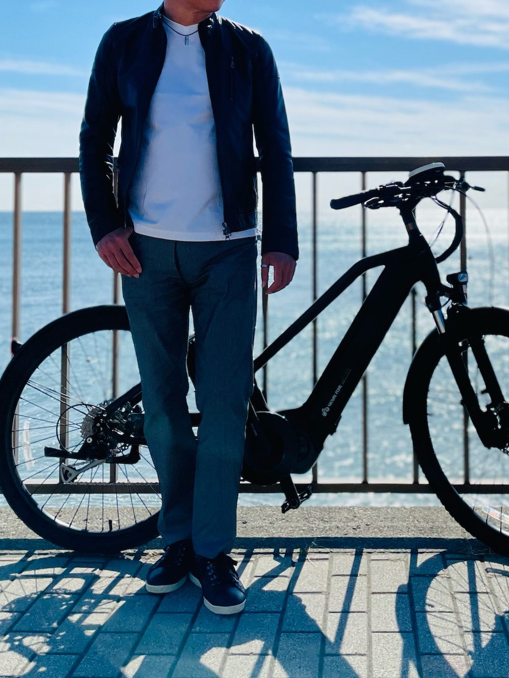 ブラック系のライダースジャケット、ホワイト系のTシャツ/カットソー、グレー系のチノパンツを着用したメンズの秋コーディネートの2枚目の写真