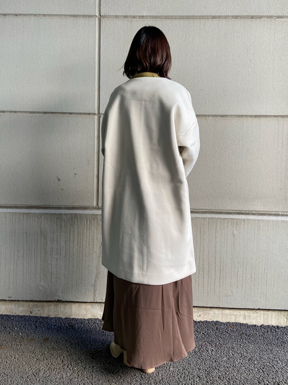 ベージュ系のその他アウター、グリーン系のニット/セーター、ブラウン系のスカートを着用したレディースの冬コーディネートの3枚目の写真