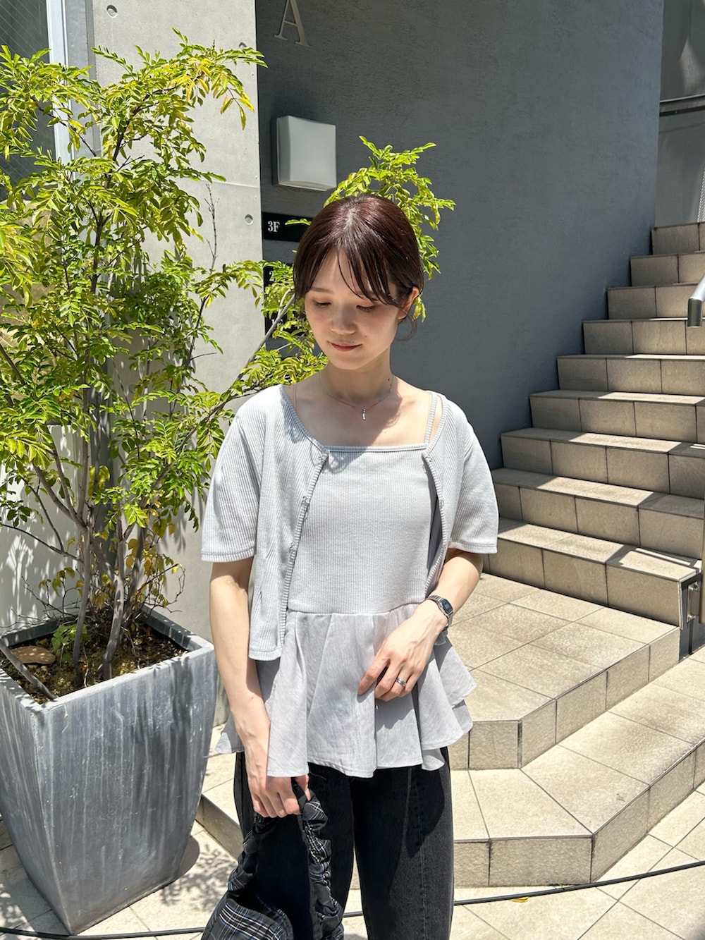 ブラック系のデニムパンツ、ホワイト系のサンダル、ブラック系のトートバッグを着用したレディースの春コーディネートの2枚目の写真