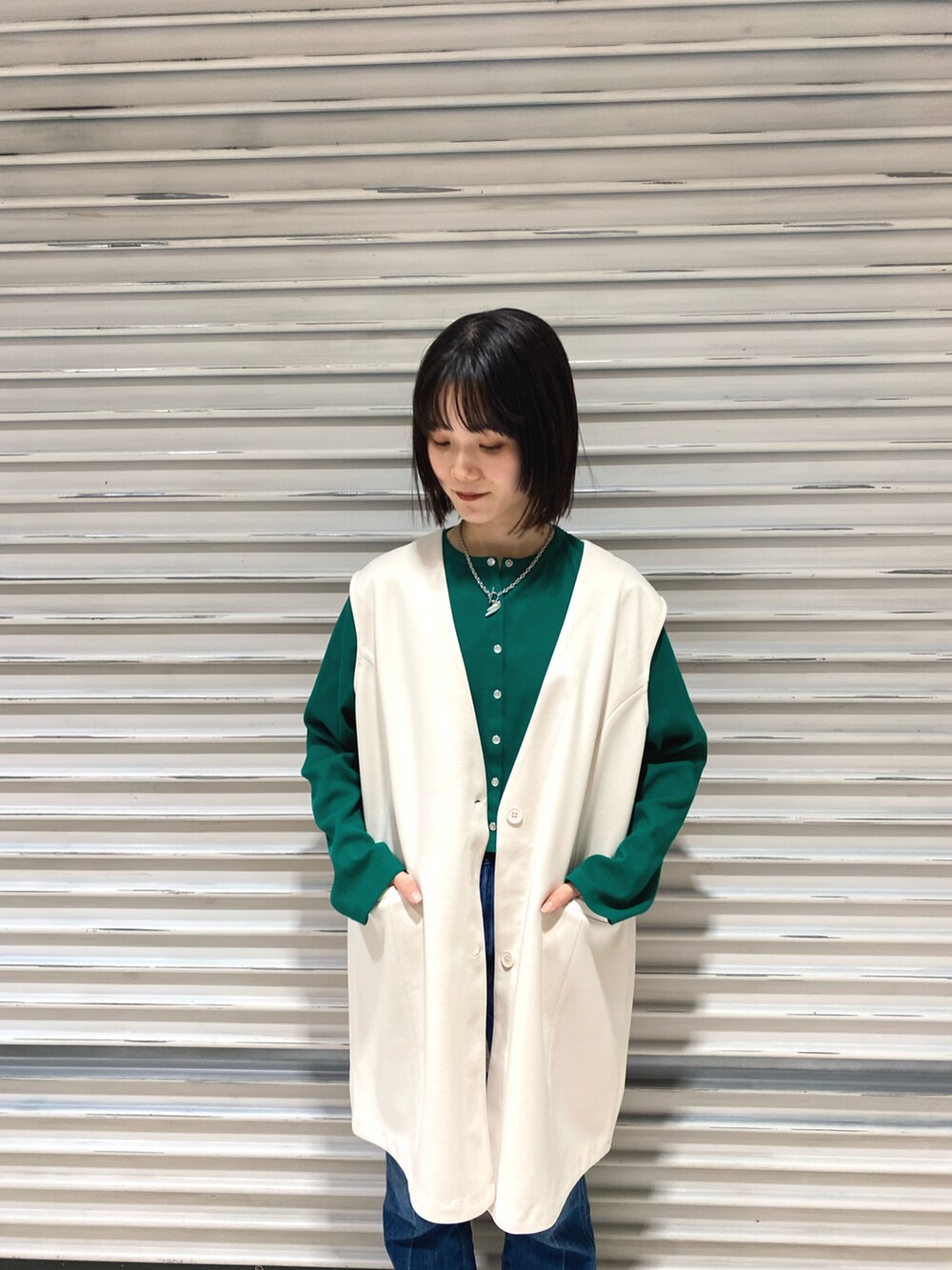グリーン系のカーディガン/ボレロ、ブルー系のデニムパンツ、ブラック系のサンダルを着用したレディースの冬コーディネートの2枚目の写真