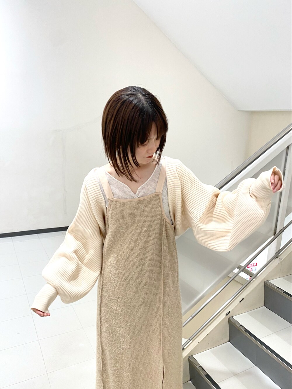 ホワイト系のカーディガン/ボレロ、ベージュ系のワンピース、ブラック系のブーツを着用したレディースの冬コーディネートの3枚目の写真