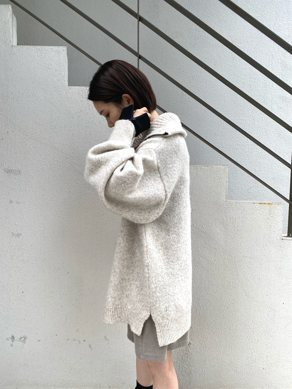ホワイト系のニット/セーター、ブラック系のTシャツ/カットソー、ブラック系のブーツを着用したレディースの秋コーディネートの3枚目の写真