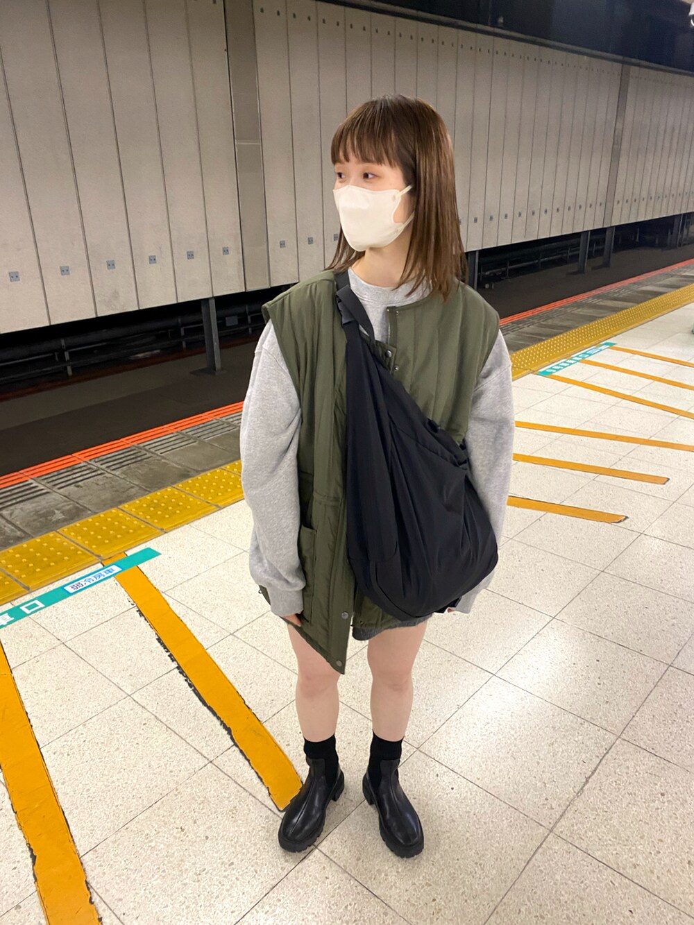 グリーン系のベスト、ブラック系のブーツを着用したレディースの秋コーディネートの2枚目の写真