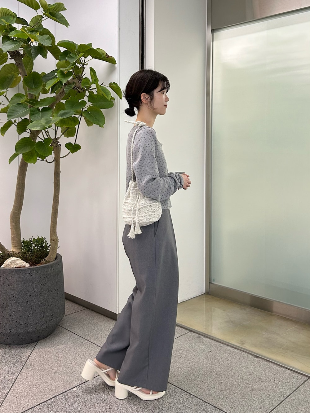 グレー系のカーディガン/ボレロ、グレー系のスラックス、ブラック系のサンダルを着用したレディースの春コーディネートの2枚目の写真