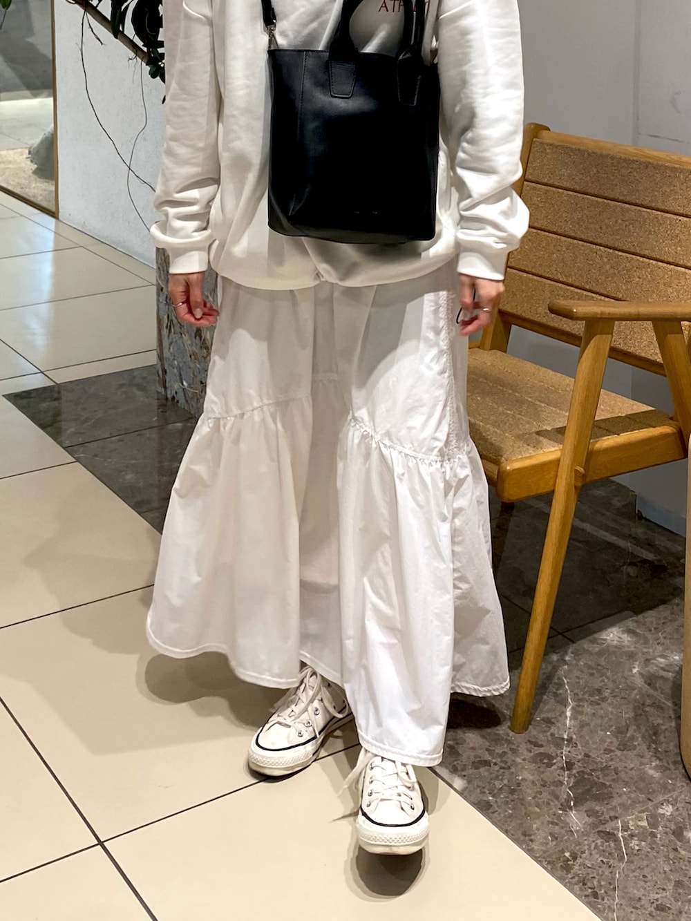 ホワイト系のスカート、ホワイト系のスウェット、ブラック系のショルダーバッグを着用したレディースの春コーディネートの2枚目の写真