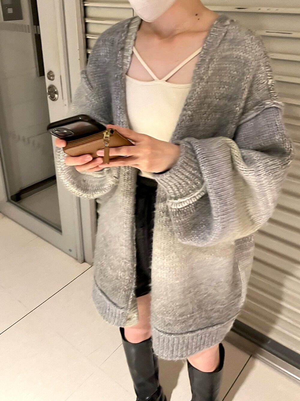 グレー系のカーディガン/ボレロ、ホワイト系のタンクトップ、ブラック系のブーツを着用したレディースの秋コーディネートの2枚目の写真