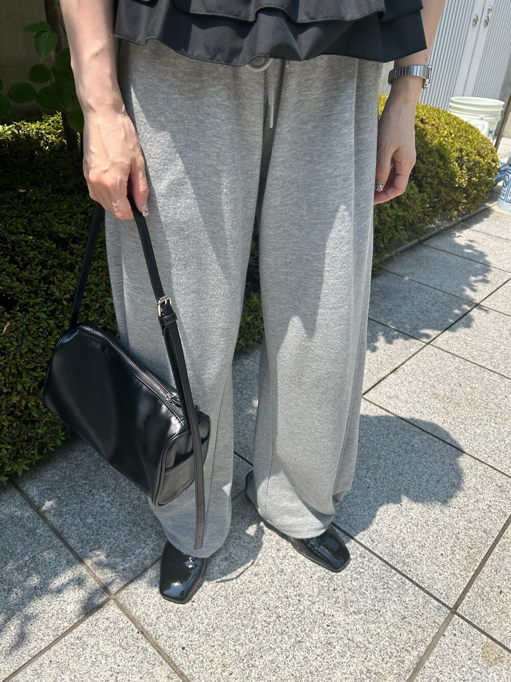 ブラック系のキャミソール、グレー系のスウェットパンツ、ブラック系のショルダーバッグを着用したレディースの夏コーディネートの4枚目の写真