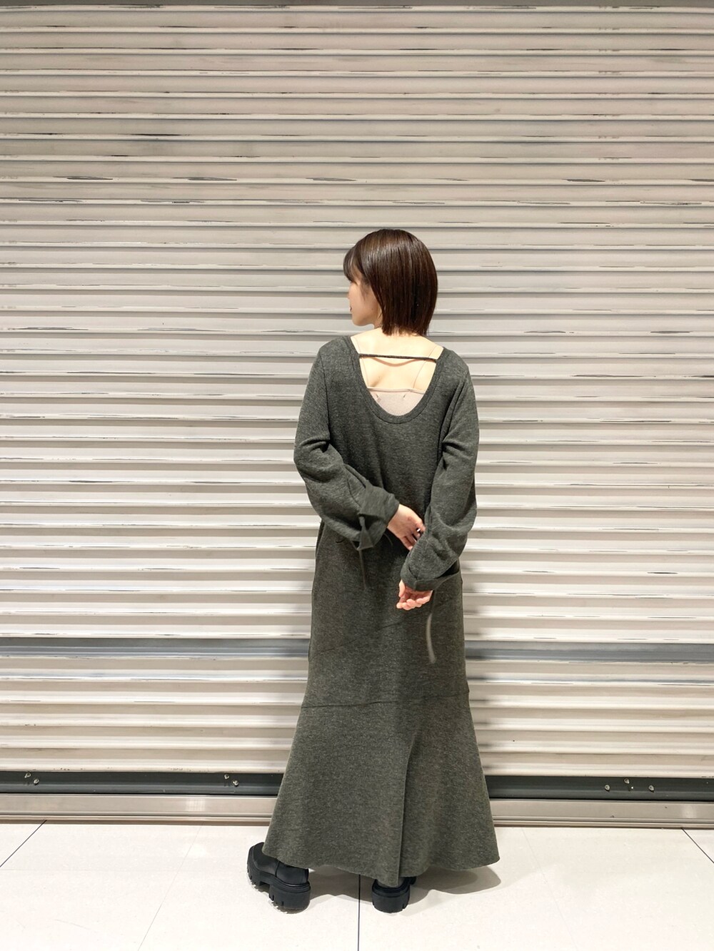 ブラック系のブーツ、グリーン系のワンピース、ホワイト系のベストを着用したレディースの冬コーディネートの3枚目の写真