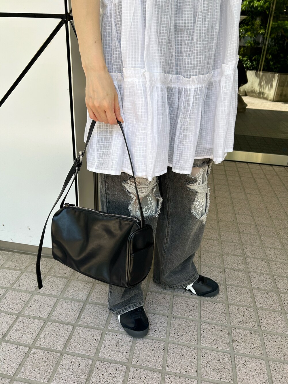 ホワイト系のチュニック、ブラック系のデニムパンツ、ブラック系のショルダーバッグを着用したレディースの夏コーディネートの4枚目の写真