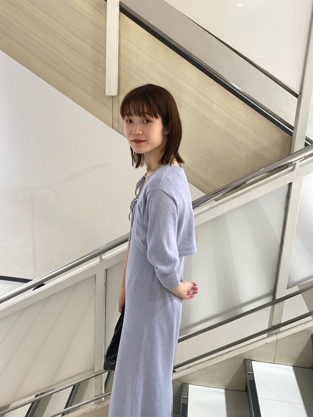 パープル系のワンピース、ブラック系のハンドバッグ、ブラック系のタンクトップを着用したレディースの春コーディネートの2枚目の写真