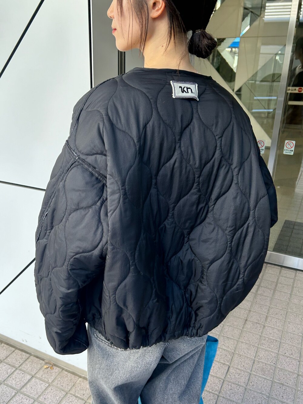 ブラック系のブルゾン、ホワイト系のカーディガン/ボレロ、ブラック系のデニムパンツを着用したレディースの夏コーディネートの3枚目の写真