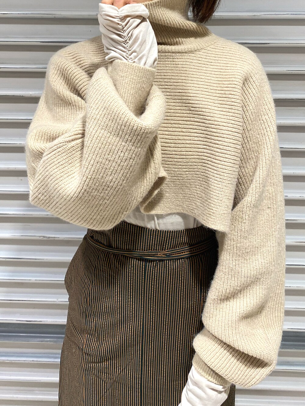 ホワイト系のニット/セーター、ホワイト系のTシャツ/カットソー、ブラウン系のスカートを着用したレディースの冬コーディネートの2枚目の写真