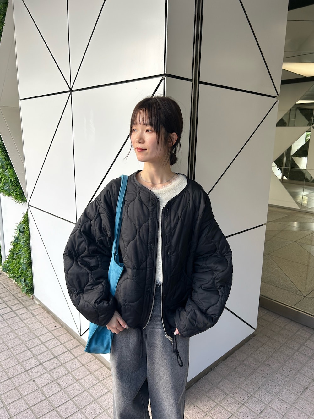 ブラック系のブルゾン、ホワイト系のカーディガン/ボレロ、ブラック系のデニムパンツを着用したレディースの夏コーディネートの2枚目の写真